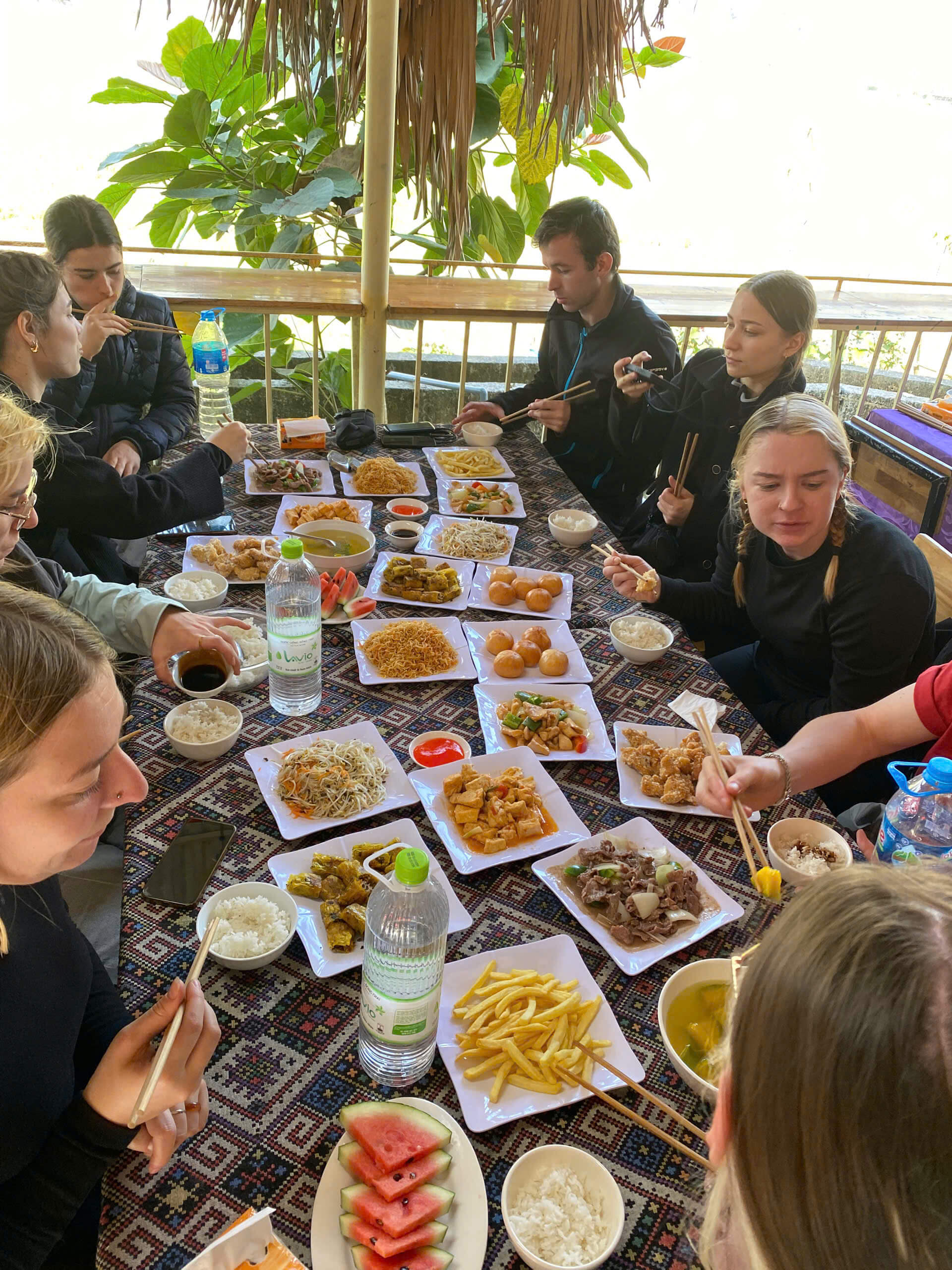 Travelers enjoying a massive and delicious family-style Vietnamese dinner at a local homestay during their Ha Giang loop adventure.